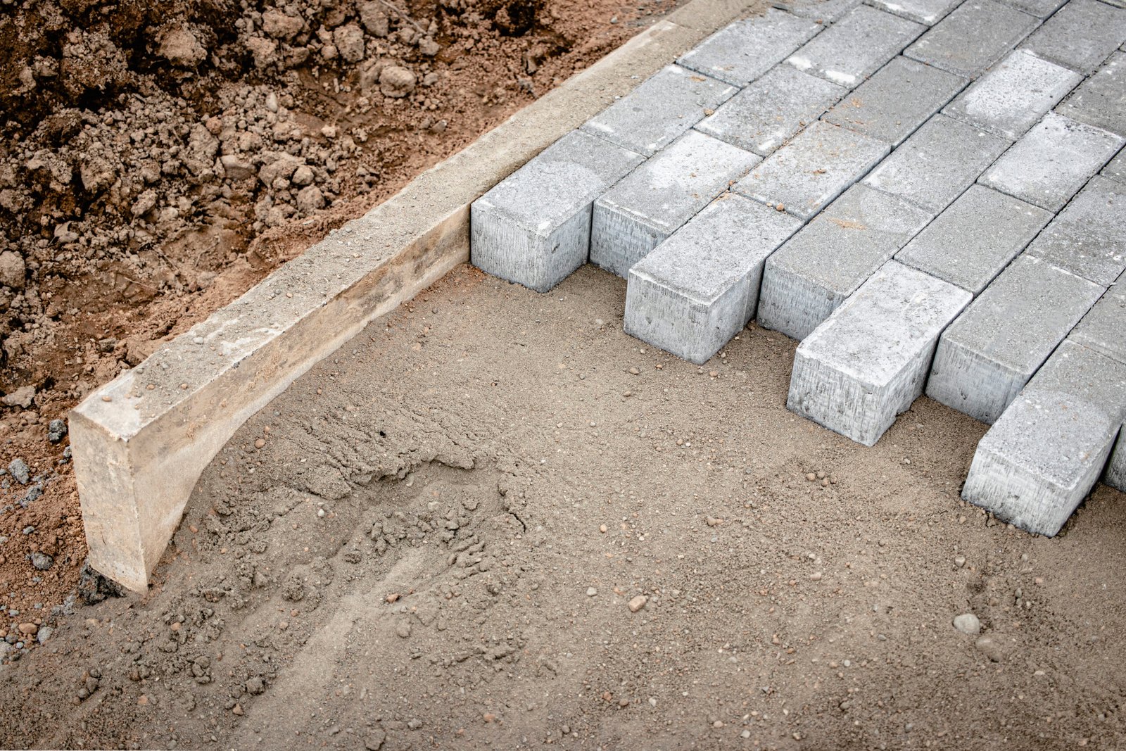 Pavement repair and laying of paving slabs on the walkway, stacked tile cubes on the background. Laying paving slabs in the pedestrian zone of the city, sand filling. Road tiles and curbs